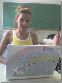 Lu Freitas usando o notebook com a arte do Blogcamp ES